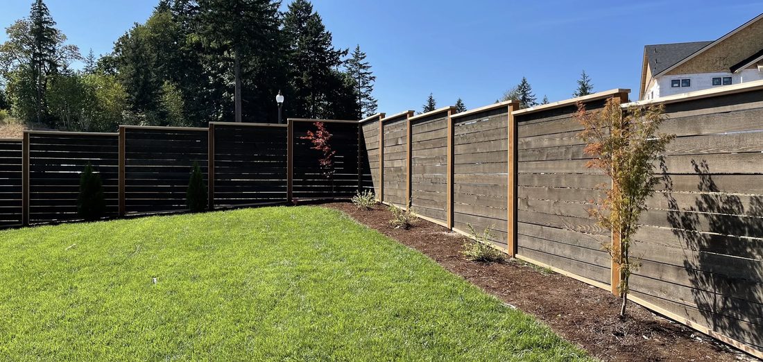 Horizontal cedar fence line along a backyard lawn